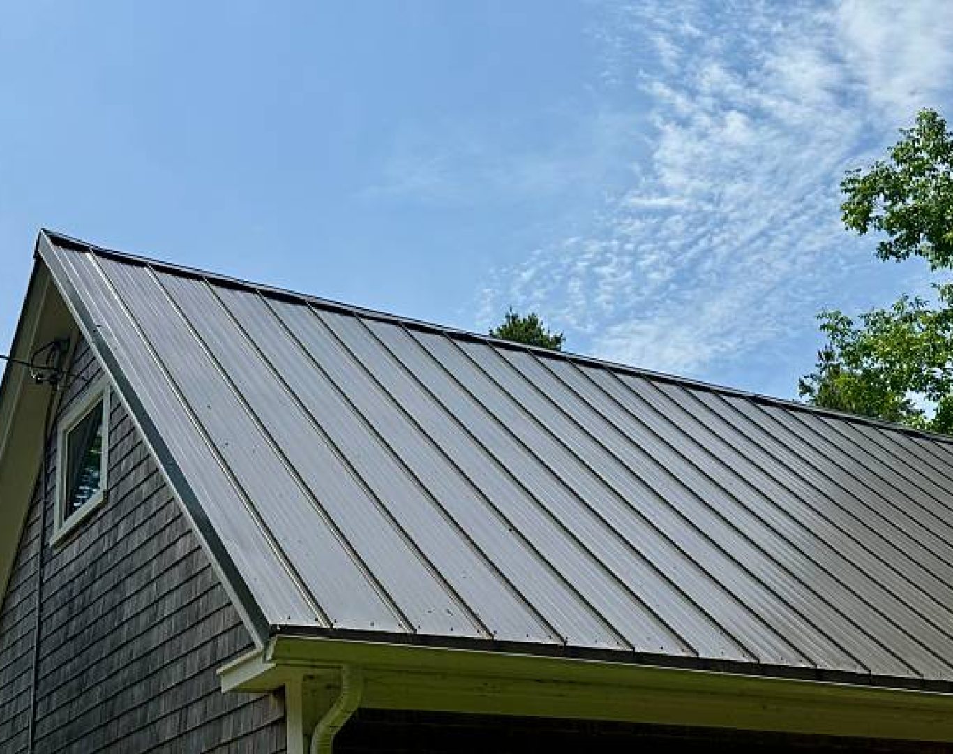 Installer measuring metal roofing trim on a Campbell, CA home before securing ridge components